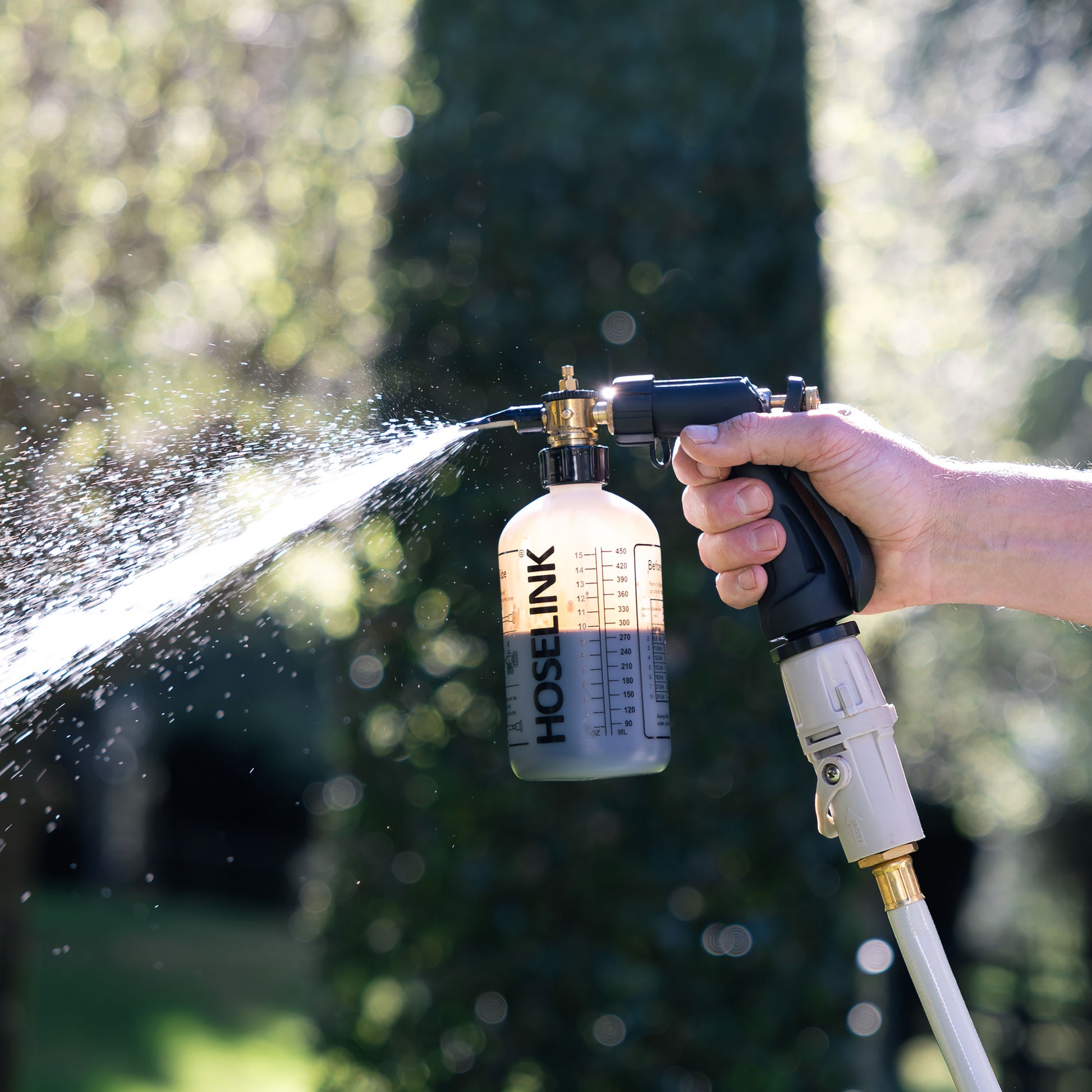 Close up of Ben Hayman using fertilizer sprayer in backyard