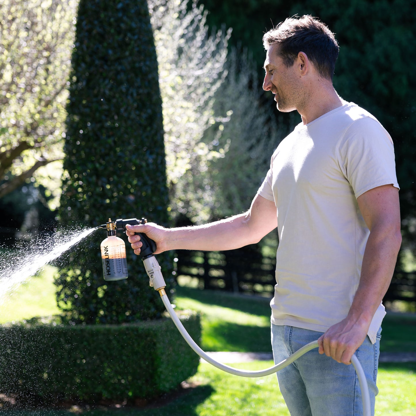 Ben Hayman using fertilizer sprayer in backyard